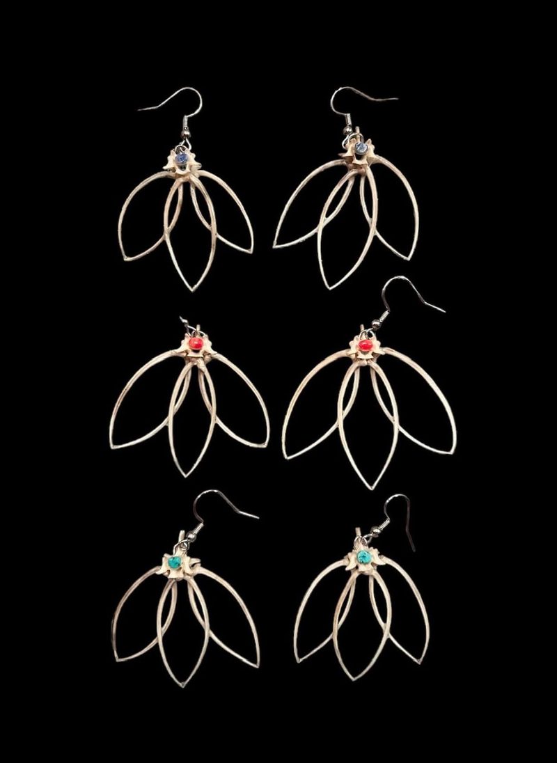 Six pairs of silver wire earrings shaped like petals, each with a small colored bead, on black.